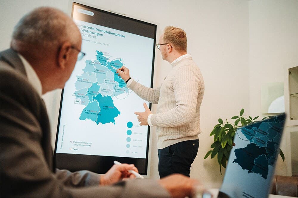 Besprechung einer Deutschlandkarte mit regionalen Immobilienpreisen: Die Marktkenntnis der jeweiligen Region fließt in jedes Immobiliengutachten ein.
