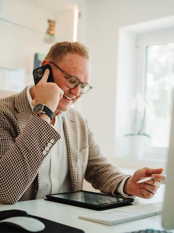 Beratungsgespräch am Telefon im Büro: Die Eckdaten eines Objekts werden aufgenommen, um zu prüfen, ob ein Immobiliengutachten fachlich sinnvoll ist.